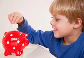 boy inserting money in piggy bank