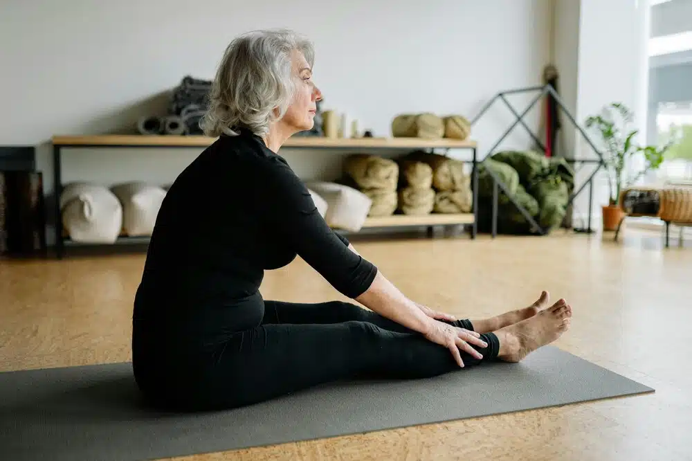 Old woman performing stretches on a yoga mat